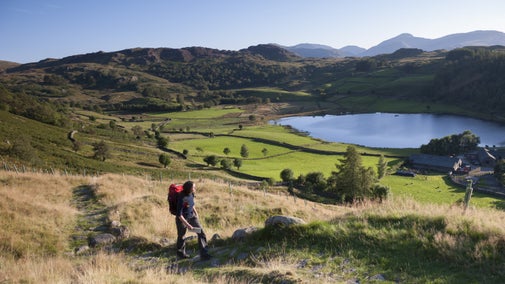 A walker enjoys the views of the village of Watendlath on a beautiful summer's day